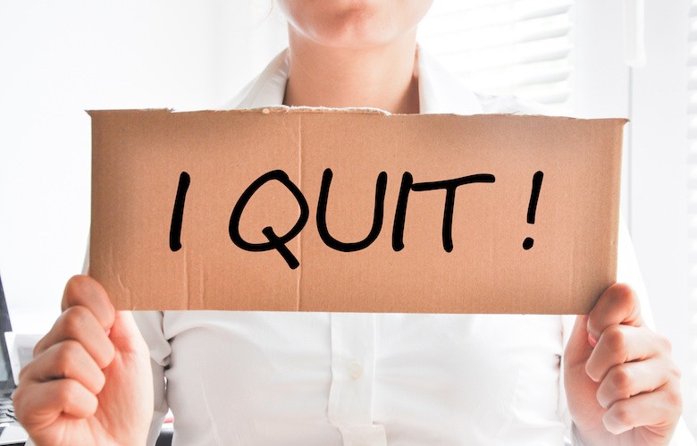 a woman holding a sign that says "I QUIT"