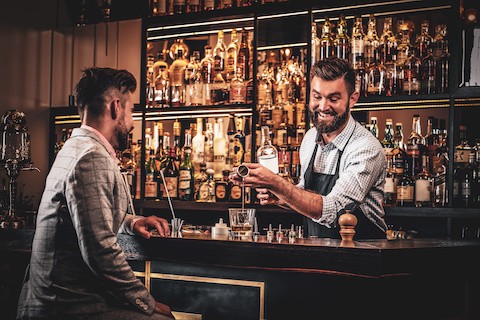 bar manager pouring drinks at his job, though it is only a small part of a bar manager job description