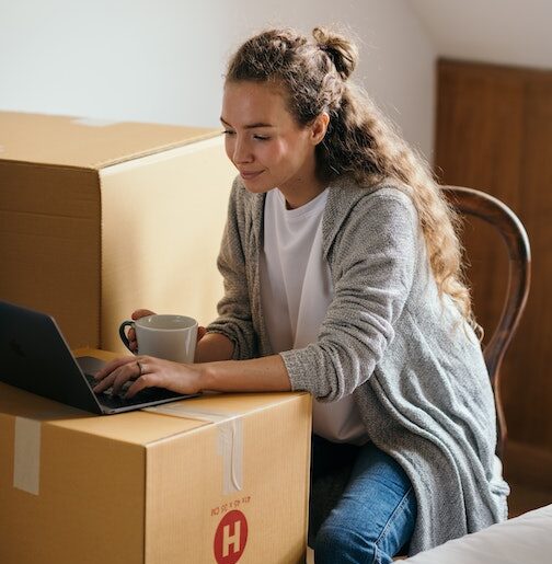 woman job searching on her computer while also packing up her home